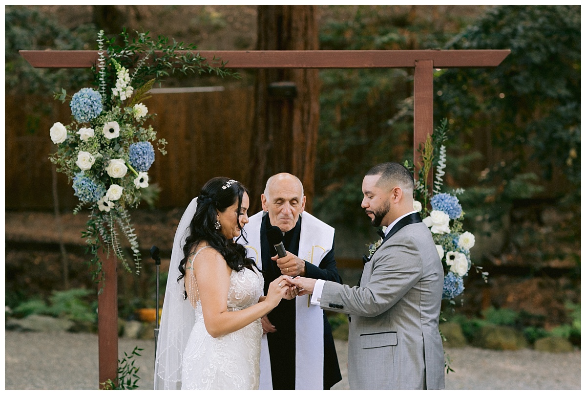 Bride places grooms wedding ring on his ring finger