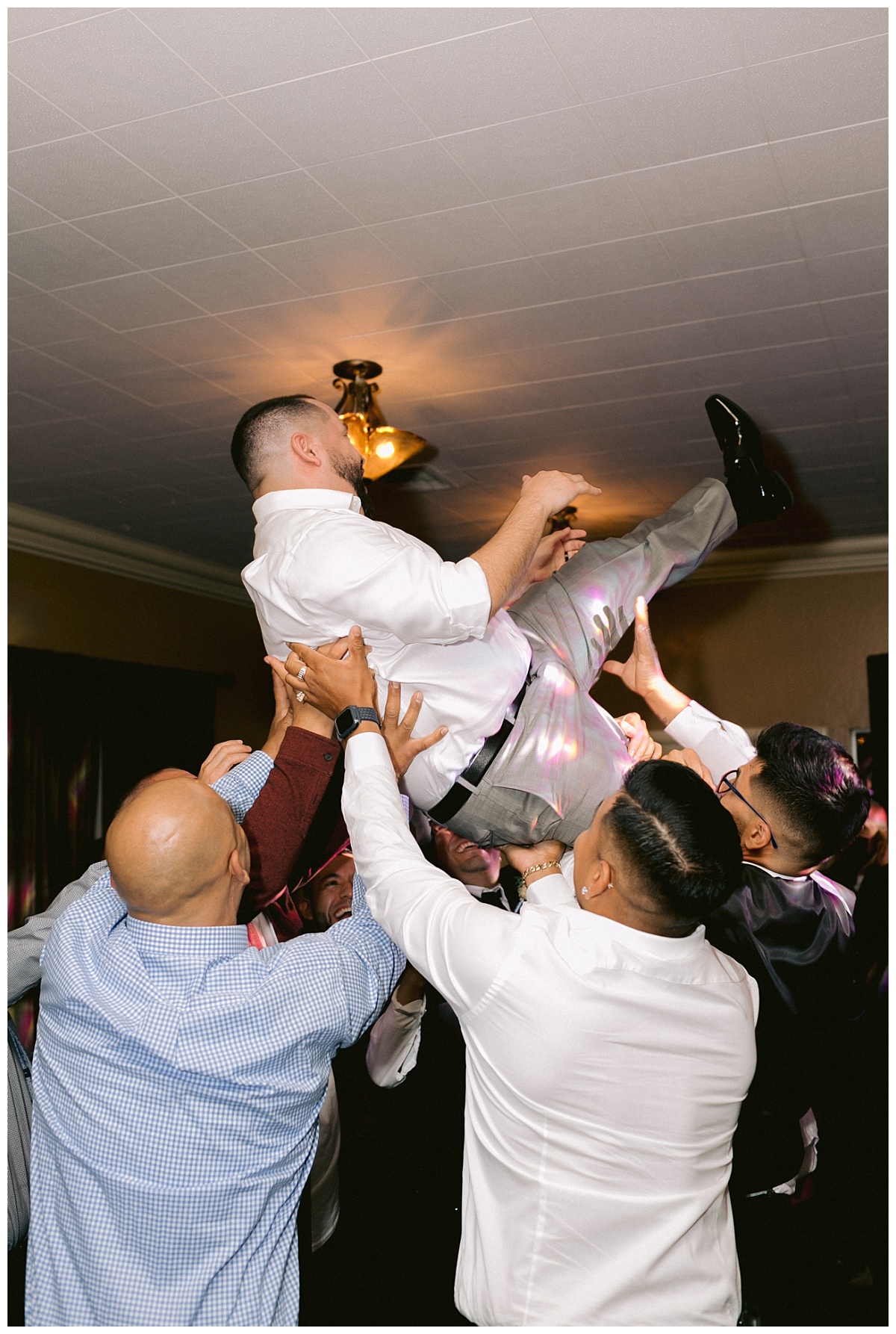 Friends lift the groom up on the dance floor