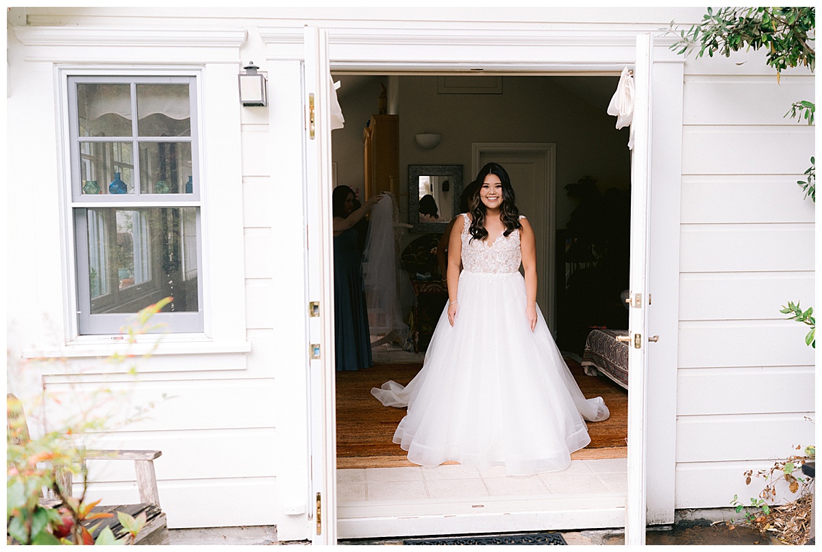 Brianna smiling in the doorway of the Hastings House before her Half Moon Bay Elopement ceremony