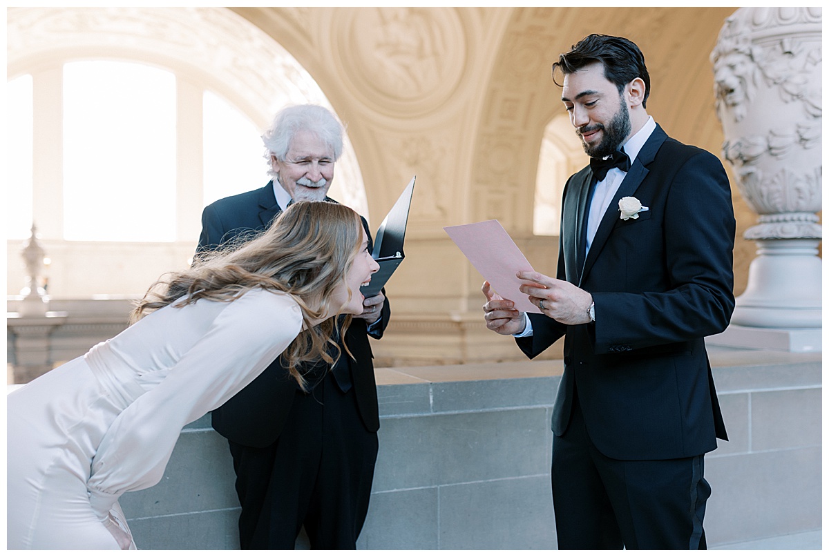 Caitlin laughing while Guilherme reads his vows