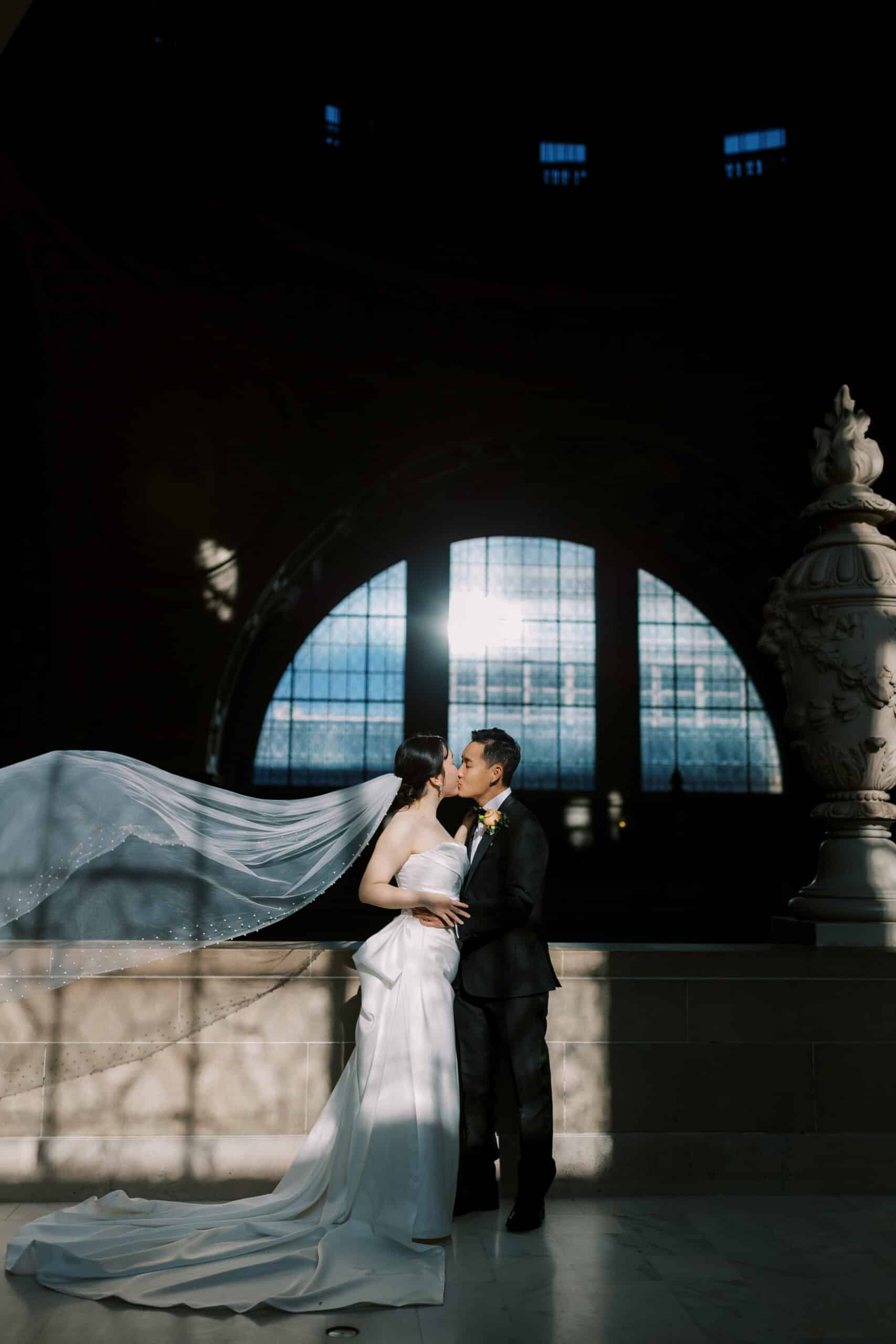 couple kissing on the fourth floor at sf city hall with veil floating behind