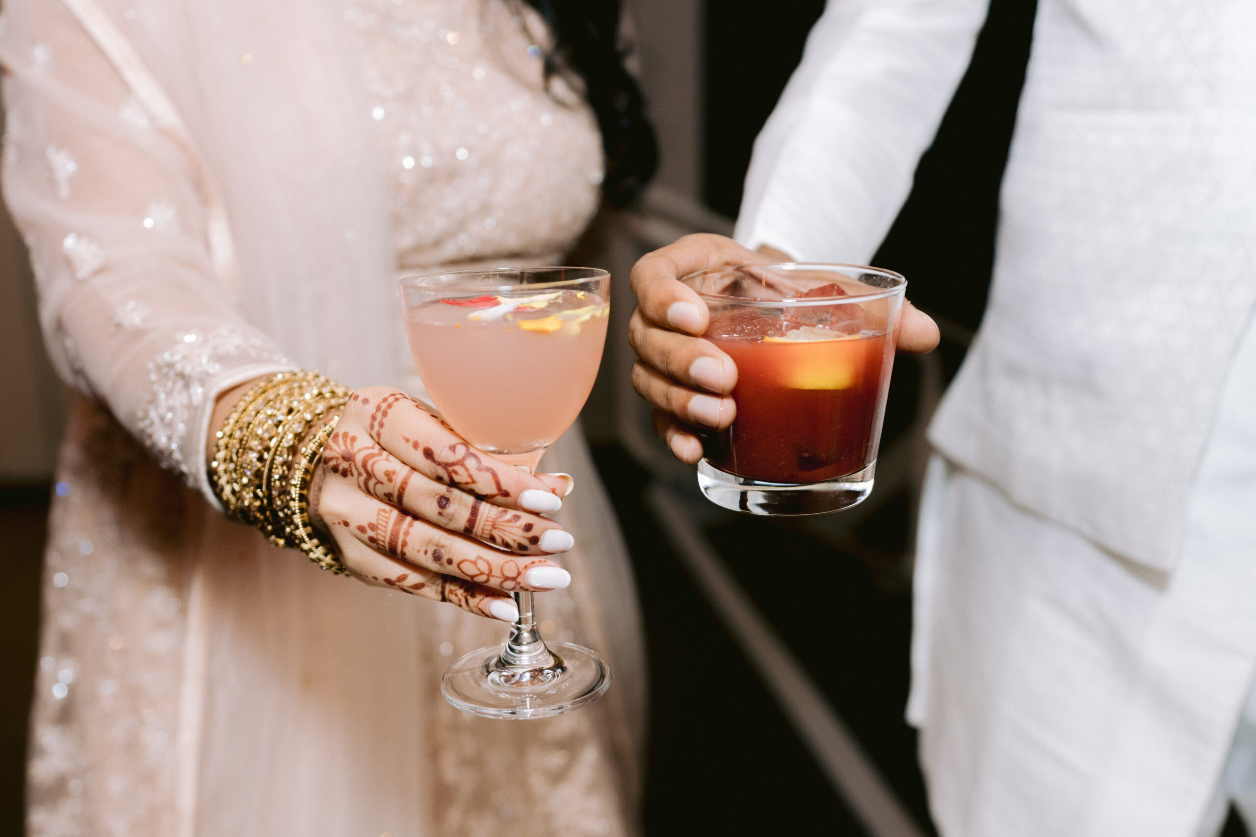 close up of married couple hands holding drinks with bridal henna