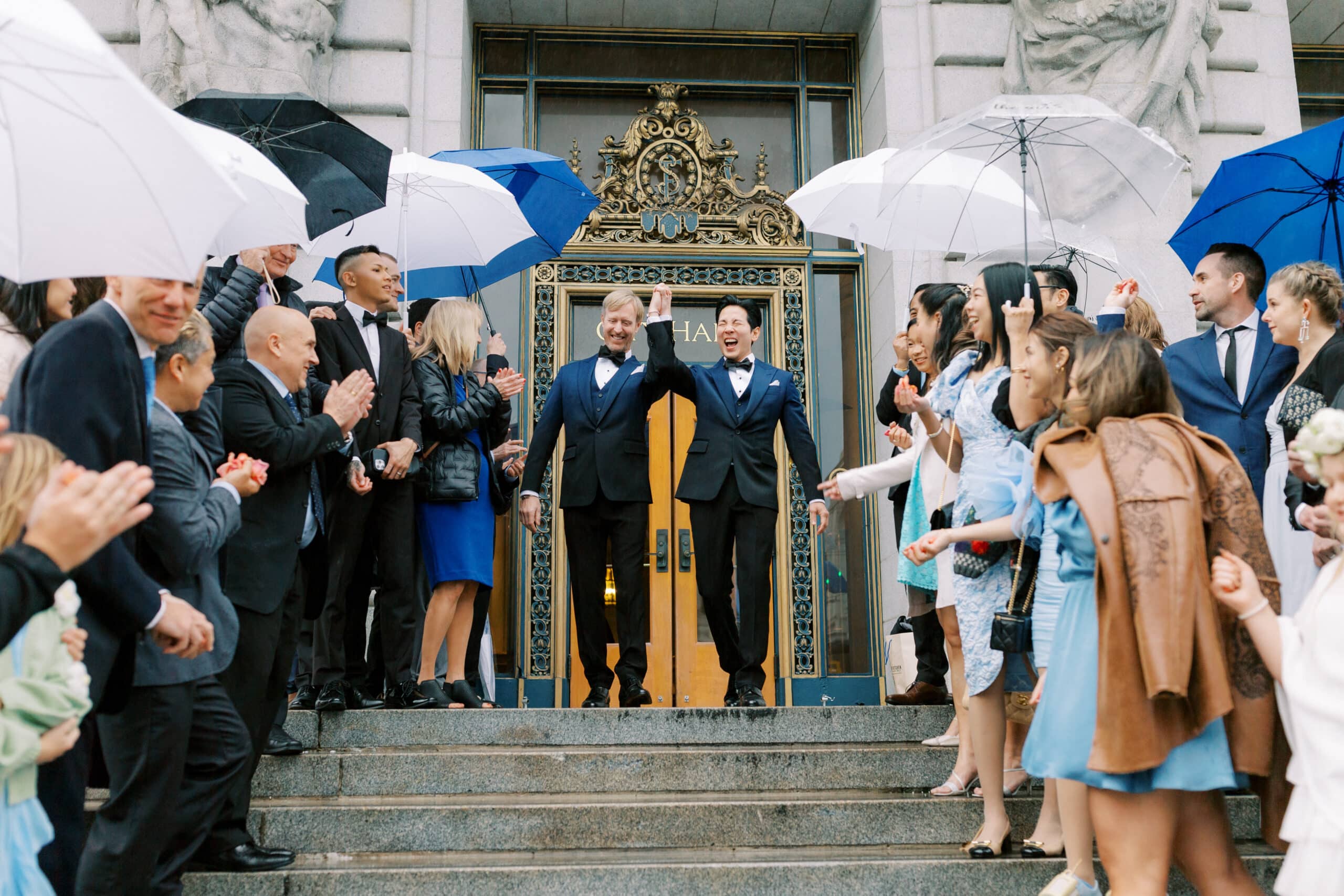 gay couple celebrating while exiting San Francisco city hall with guests on a rainy day