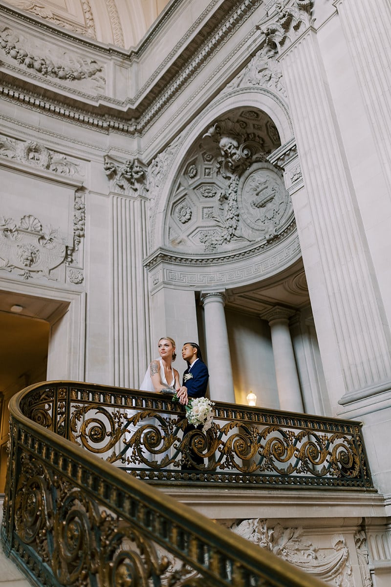 lesbian couple posing over railing after their San Francisco city hall wedding
