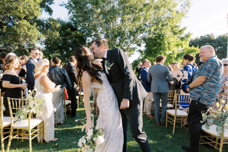 newly married couple kissing at the end of the aisle