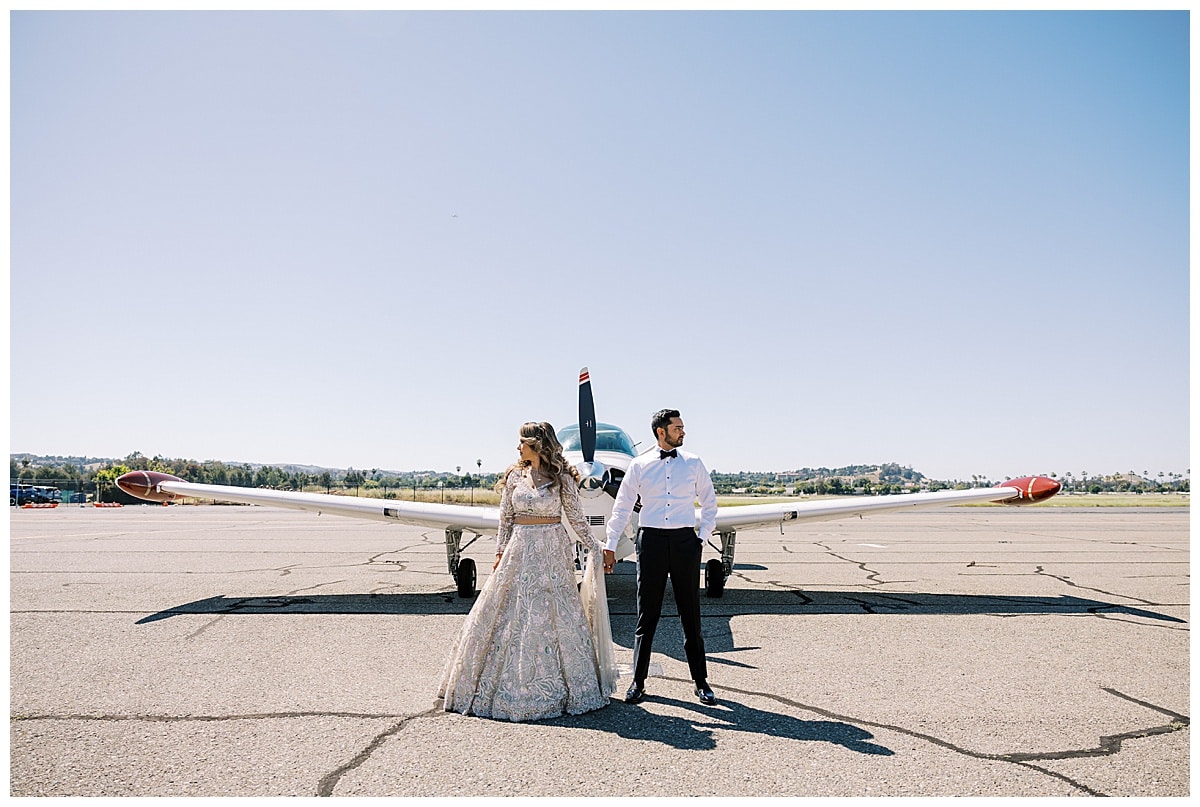 indian couple posing in front of a private plane
