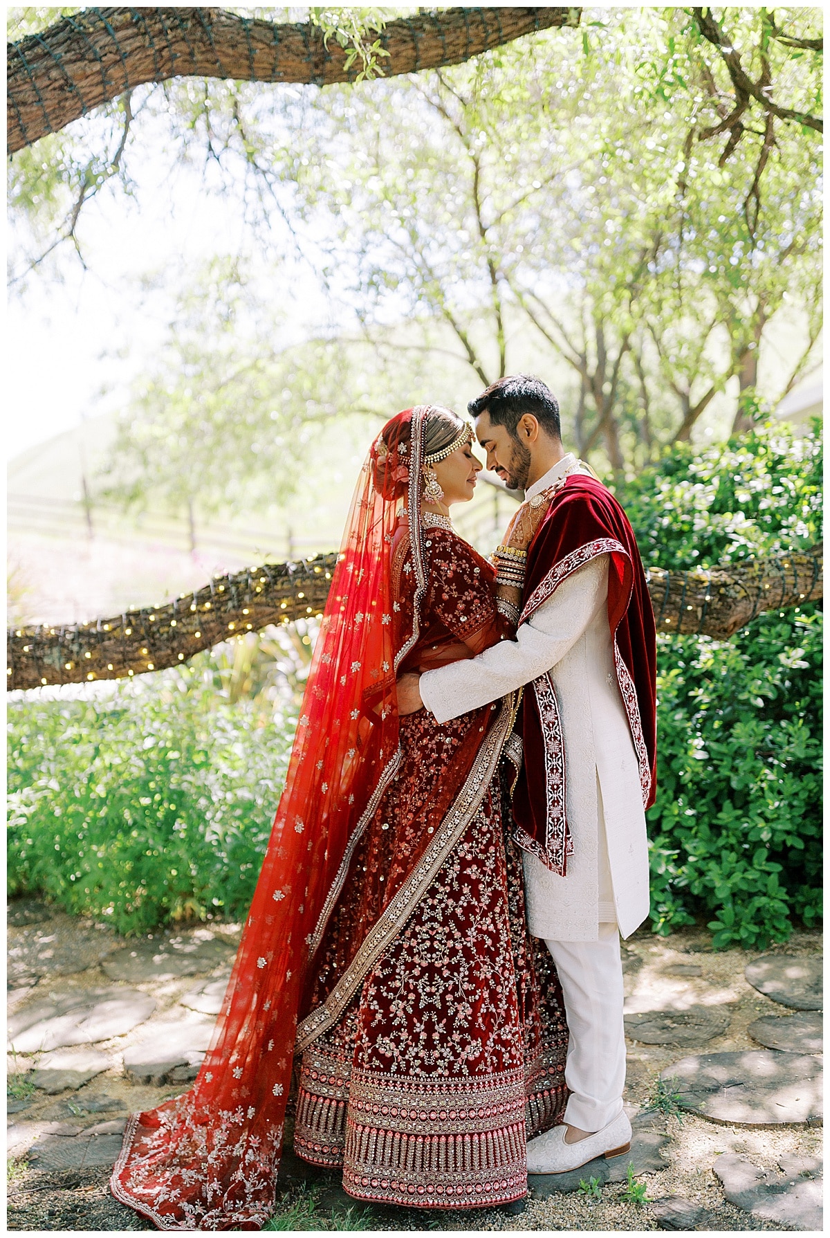 couple standing forehead to forehead under tree at Nella Terra