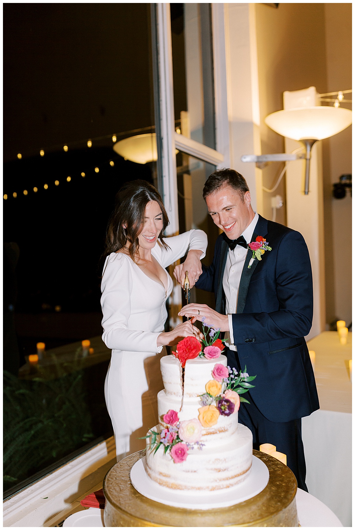 Married couple cutting wedding cake with a sword 