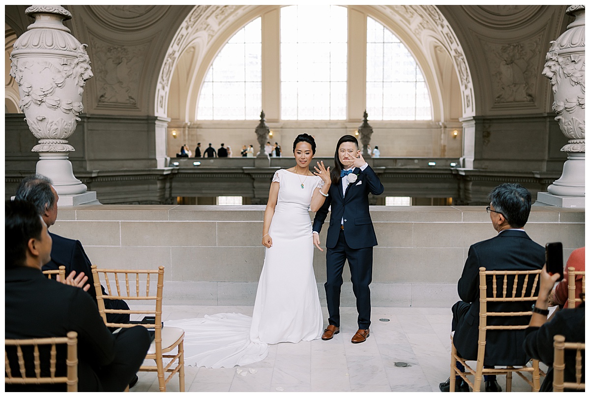 lesbian couple showing off their new wedding rings after their ceremony at San Francisco city hall
