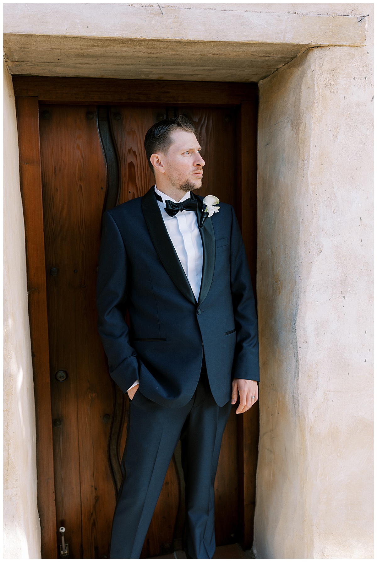groom outside of carmel mission basilica on wedding day