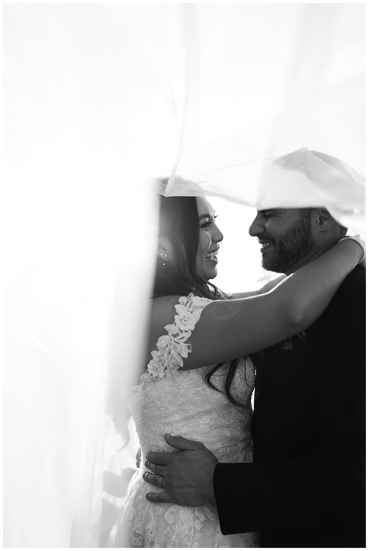 black and white portrait of couple laughing under the veil at sunset