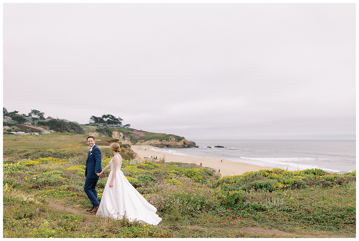 couple walking along the coast of half moon bay after their wedding ceremony at Oceano Hotel and spa