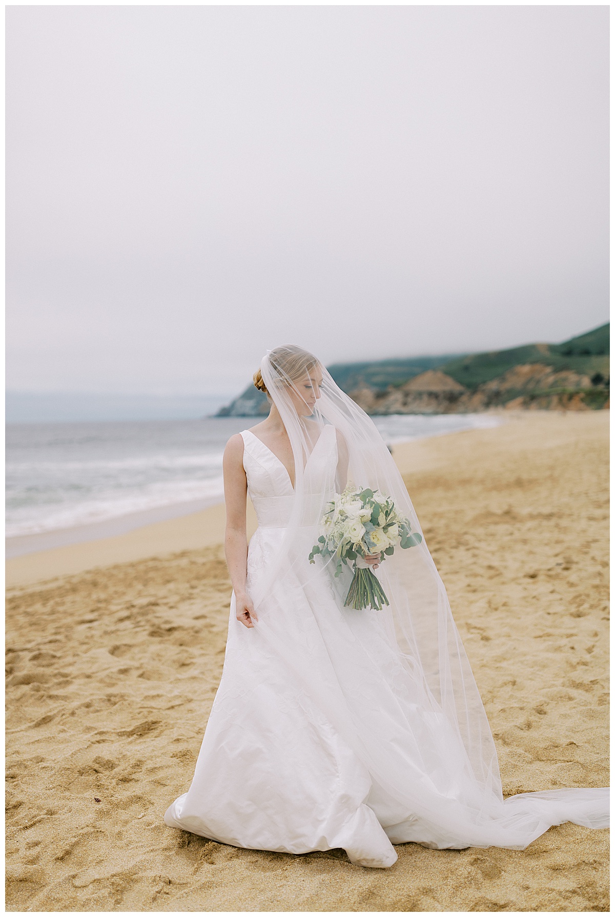 bridal portrait under the veil along the coast of half moon bay at the beach