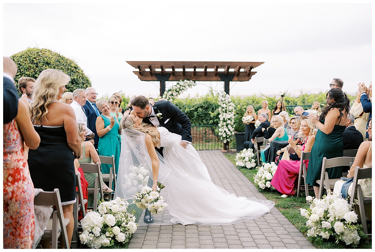 groom dips bride in the middle of the aisle after tying the knot at palm event center