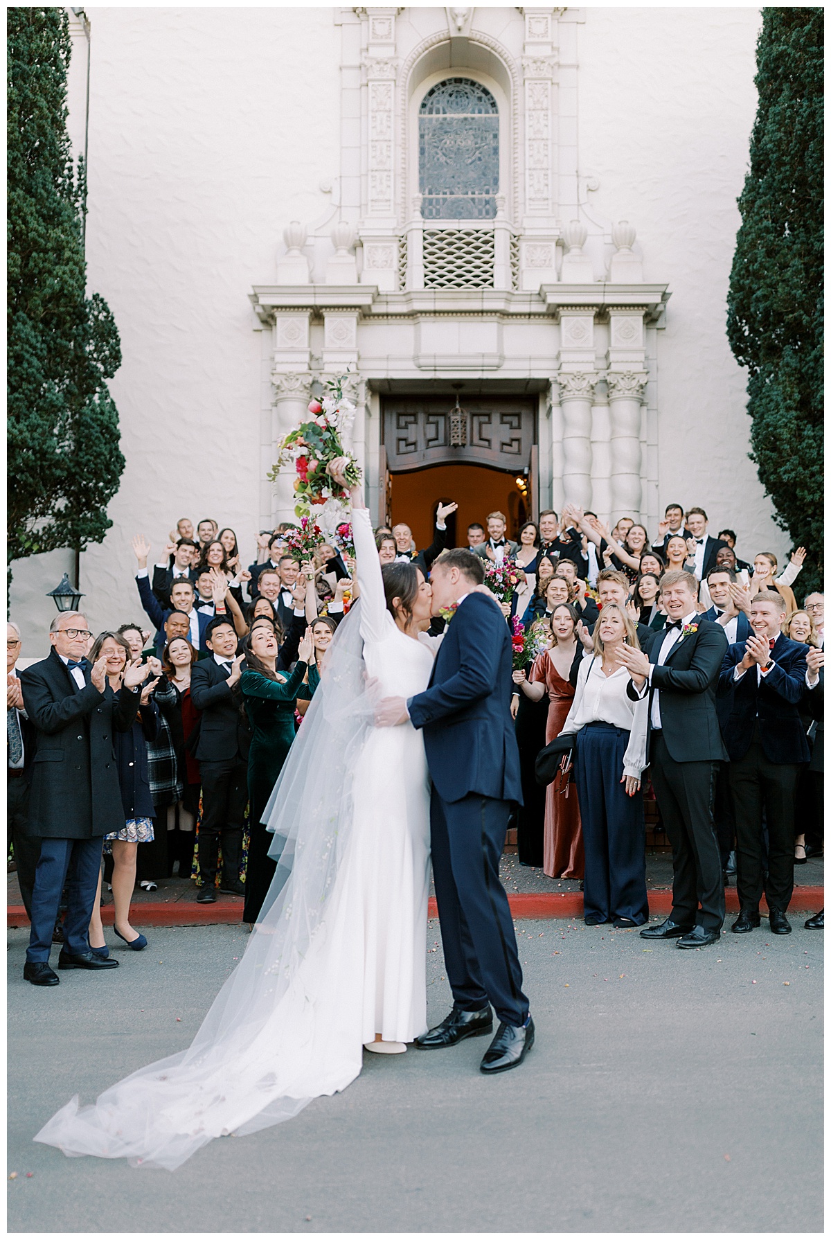 bride and groom kissing in front of group celebrating