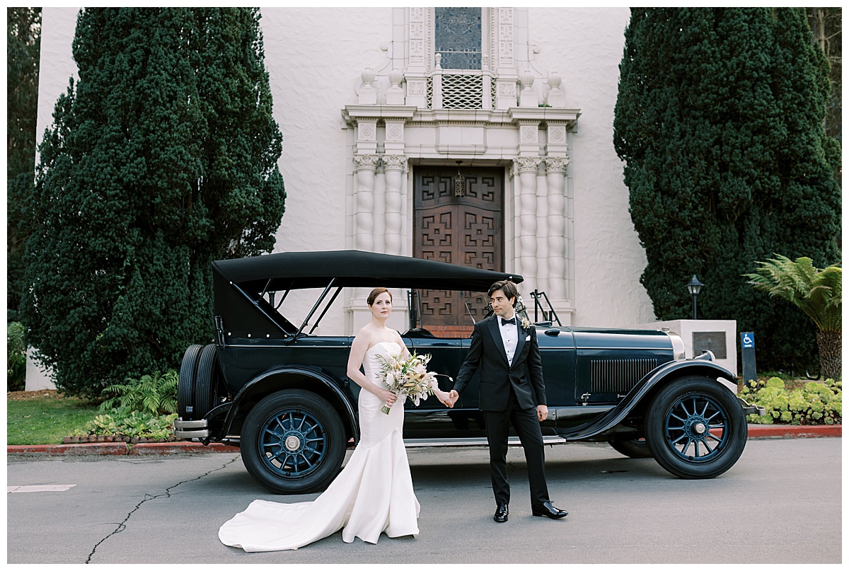 couple standing in front of vintage car outside of the presidio chapel