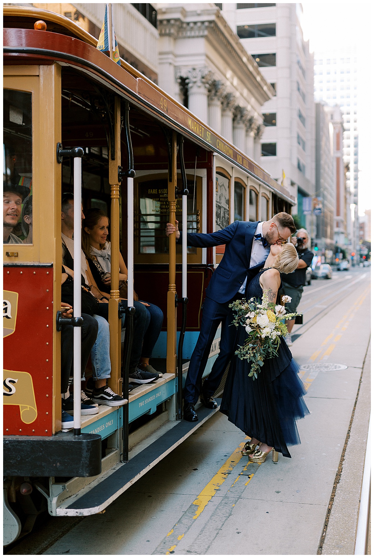 couple kissing while hanging off of a cable car in downtown san Francisco 