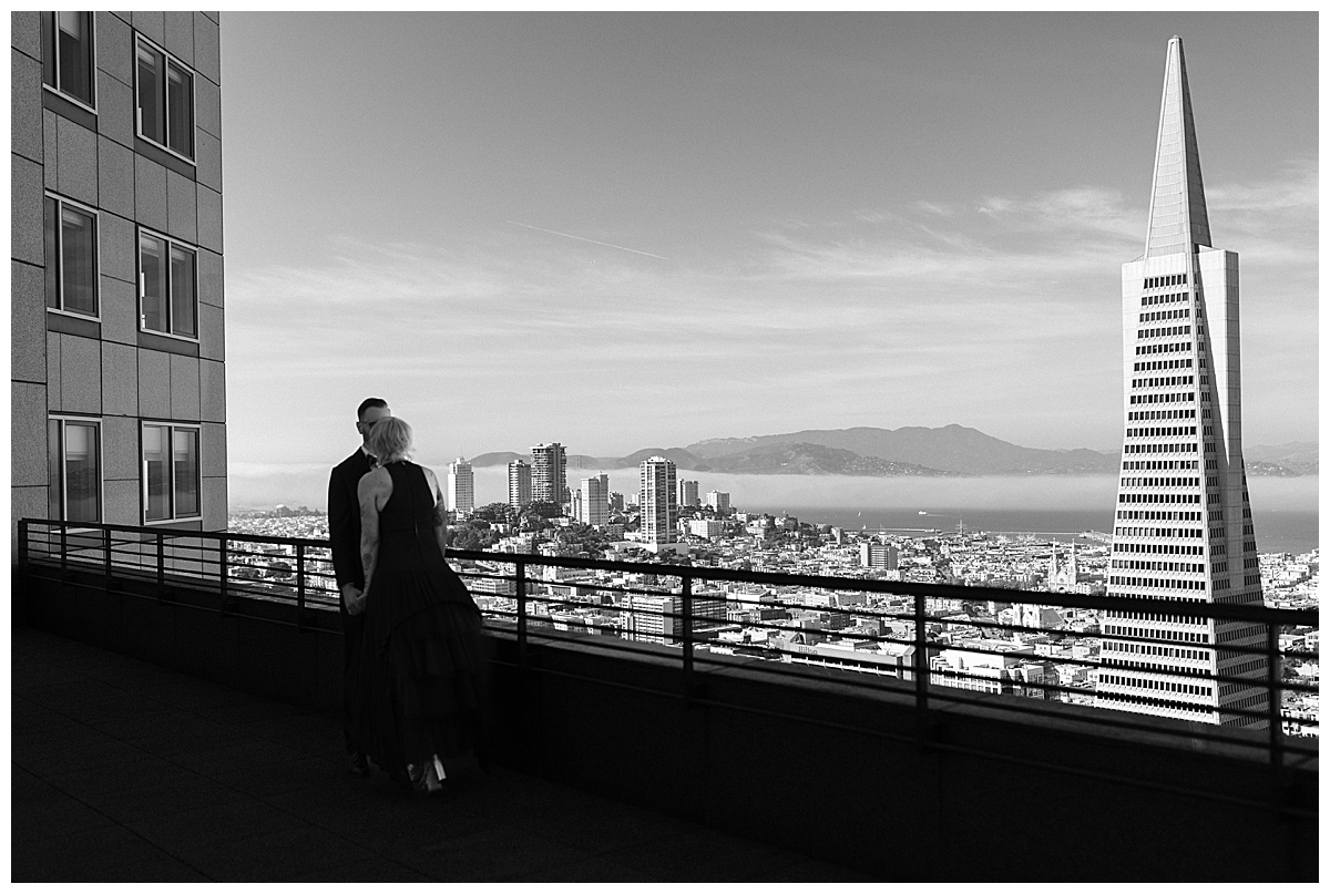 wide black and white photo of couple kissing on balcony of sf hotel