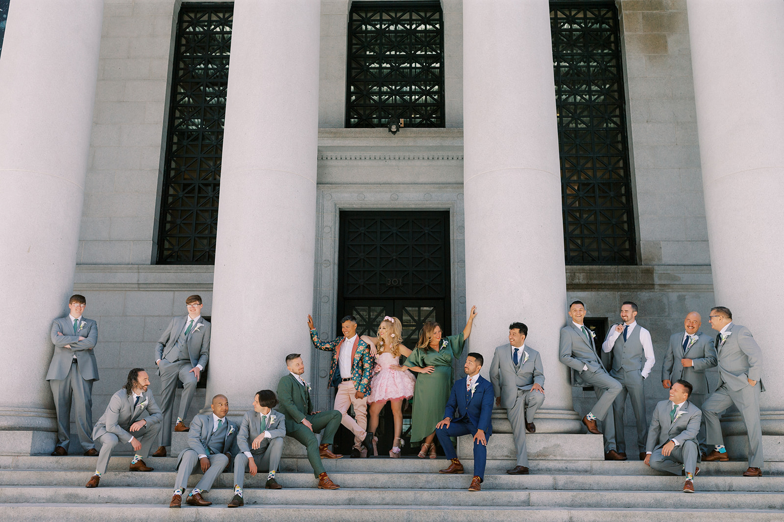 wide photo of two grooms and their wedding party on the steps outside in sf