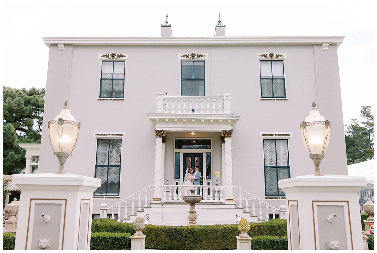 wide portrait of couple standing on front porch of Jefferson street mansion