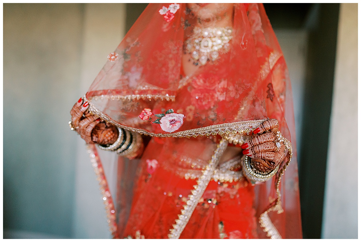 detail photo of hands and veil of indian bride in red