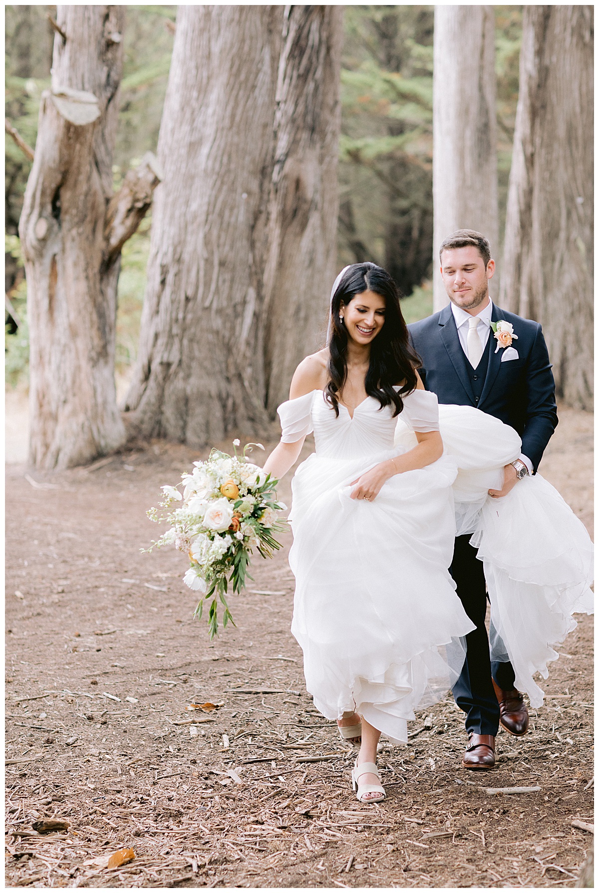 couple laughing while walking through the trees in half moon bay