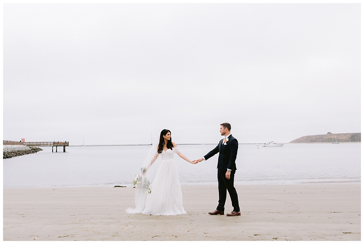 bride leading groom along beach outside of Oceano Hotel and spa