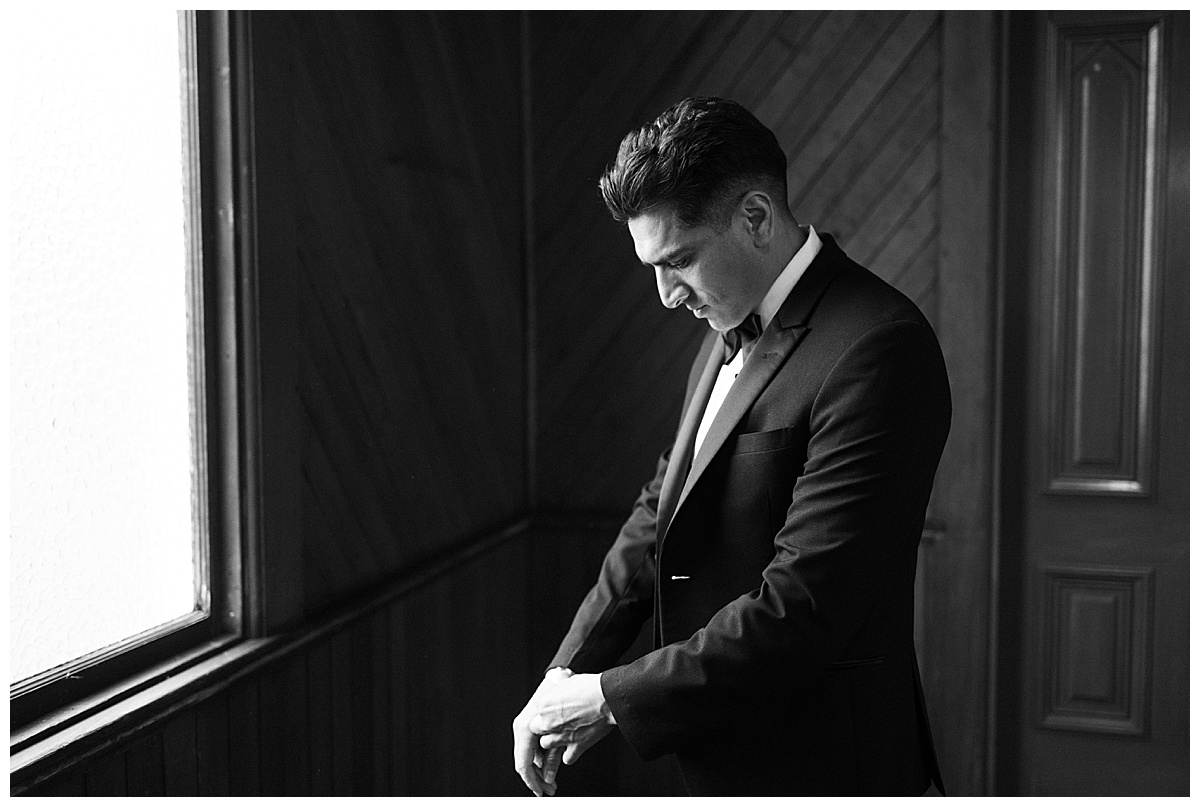 groom getting ready at window in old st Hilarys