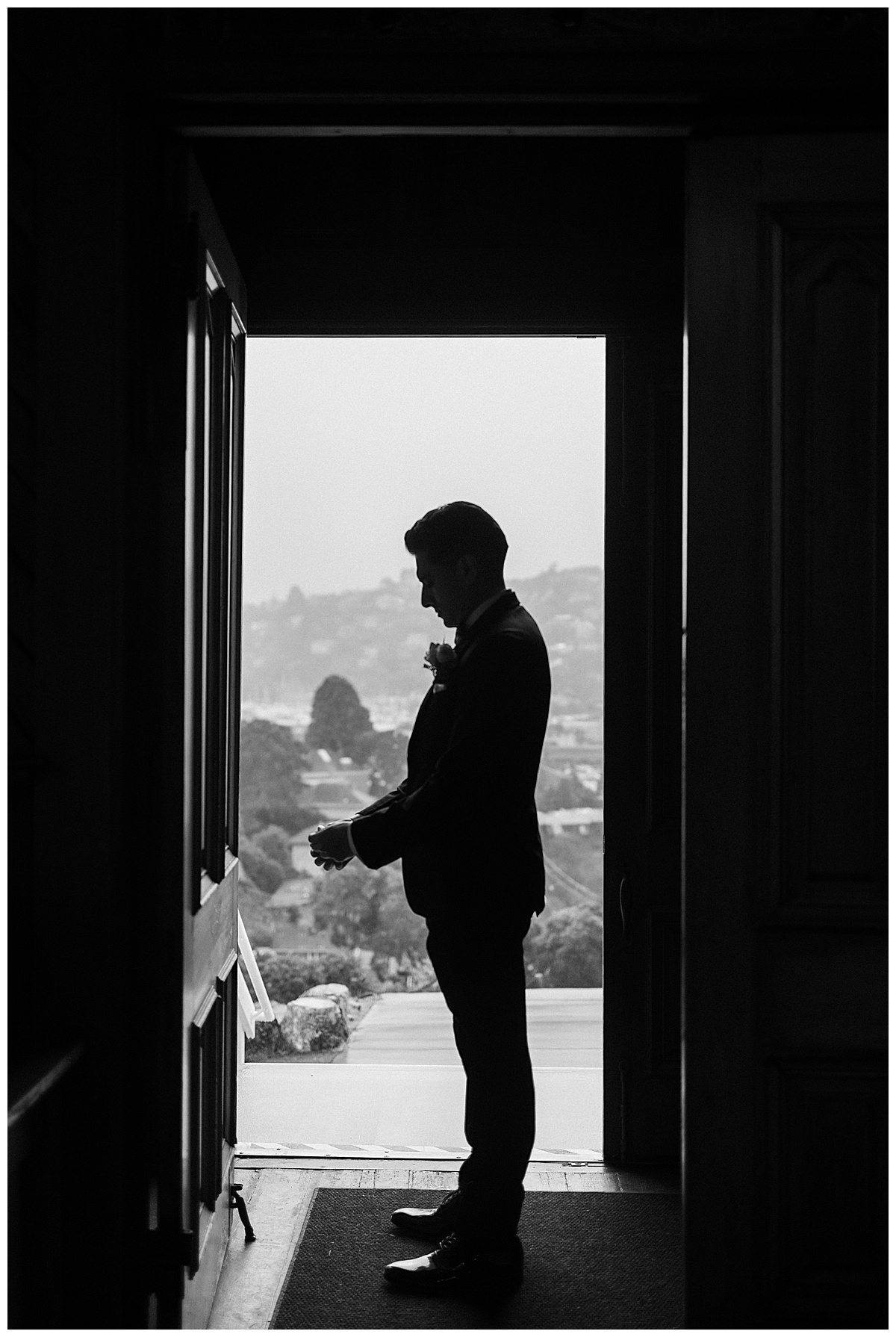 black and white silhouette of groom adjusting sleeve before wedding at old st Hilarys