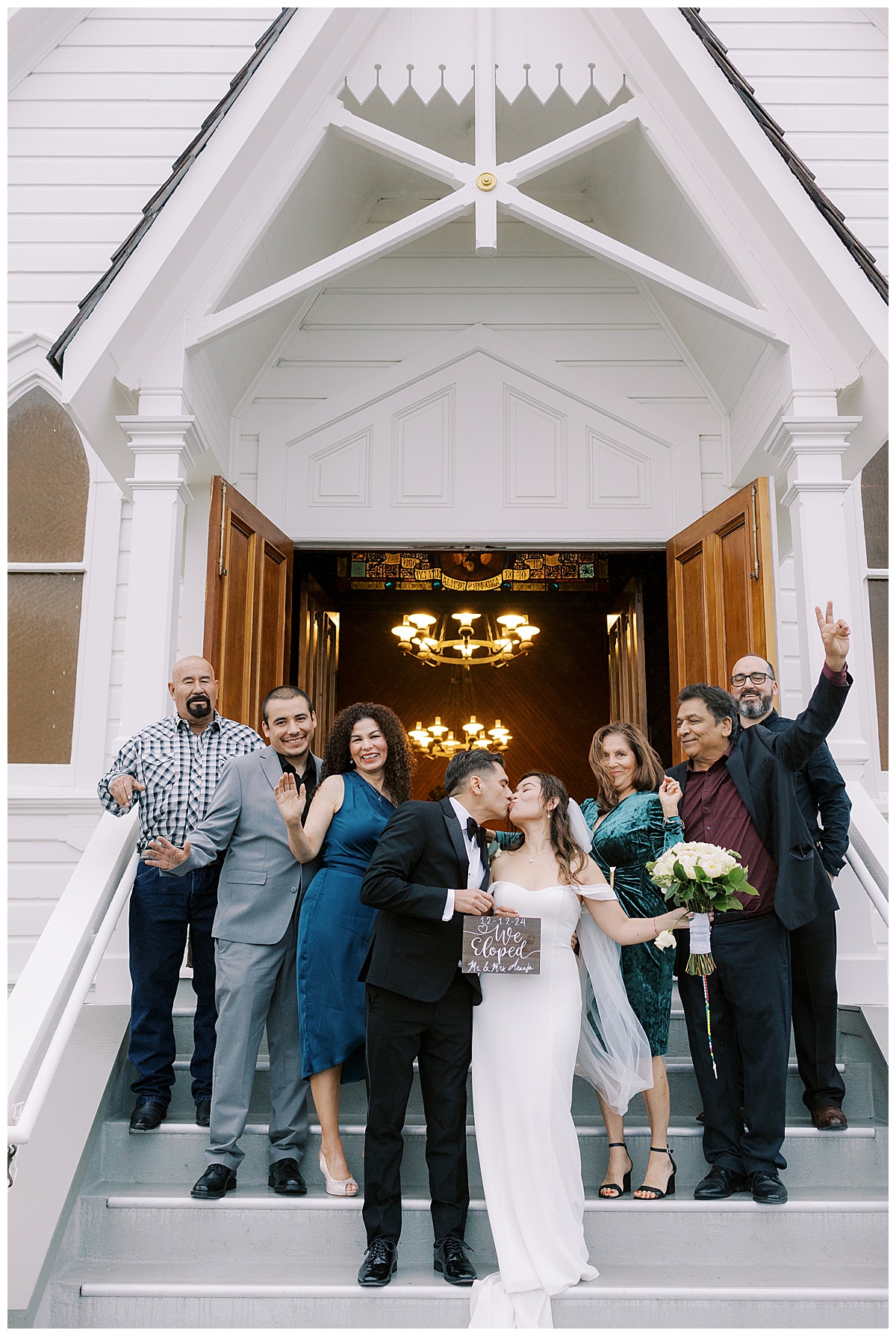 family and friends celebrating while newlywed couple kisses in front of old st. Hilary's church after the elopement 