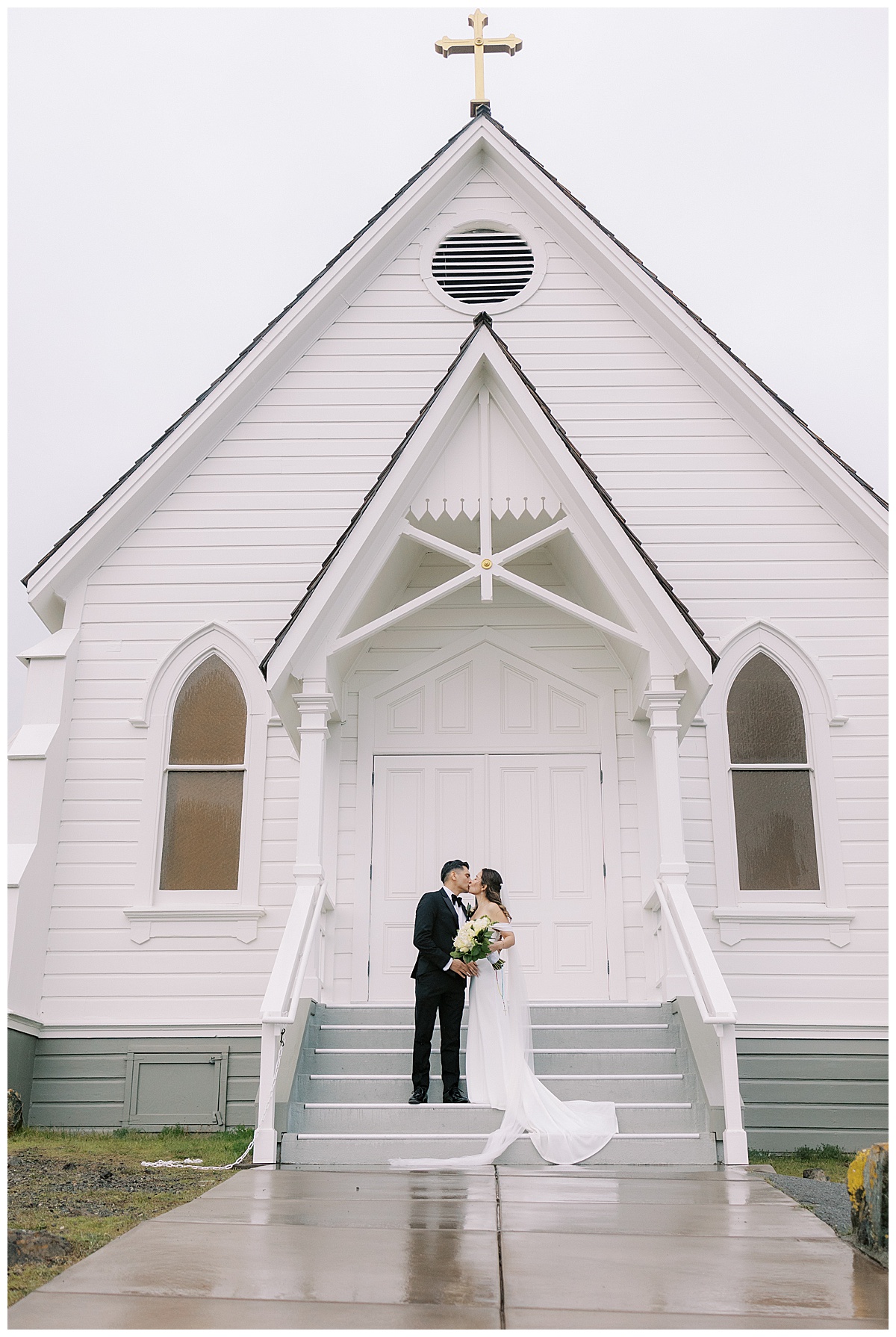 bride and groom kiss on the steps of old st. Hilary's
