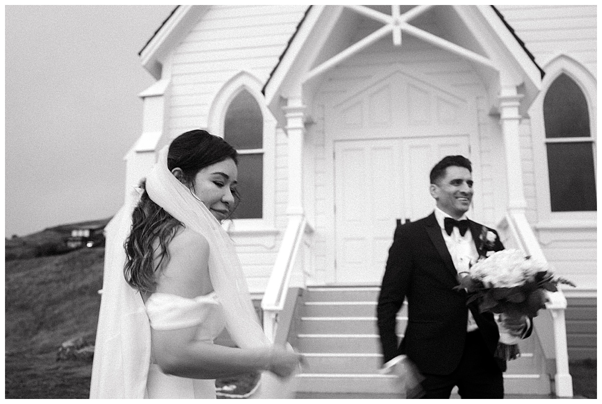 black and white photo of bride and groom standing outside the church after their wedding