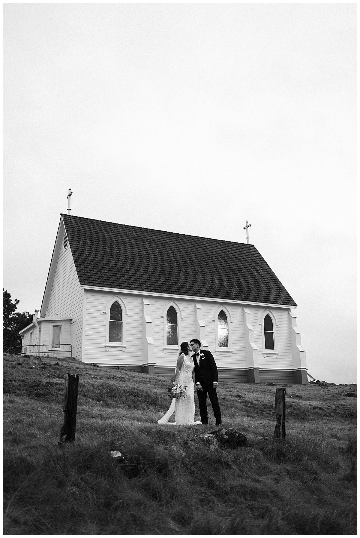 black and white photo of couple kissing in front of old st Hilarys 