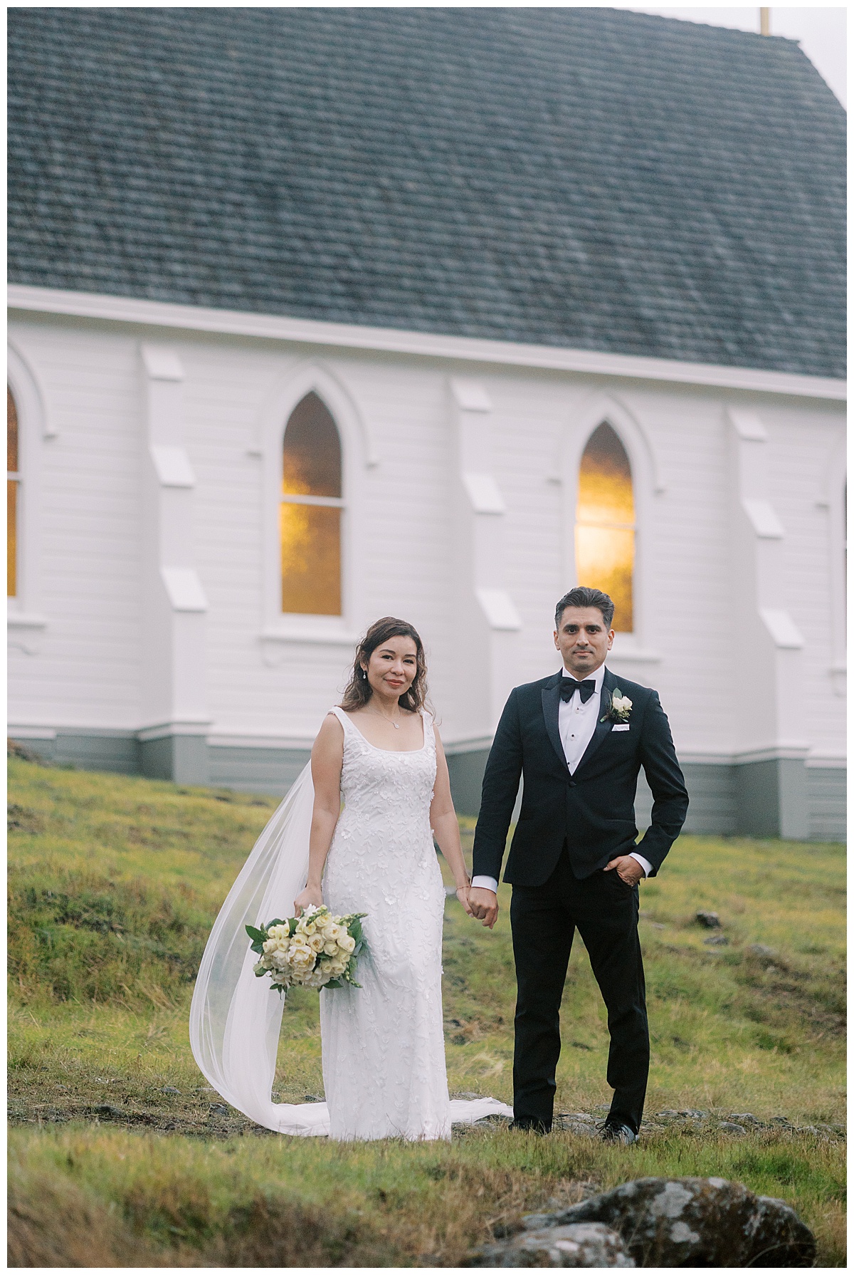 couple holding hands in front of old st Hilarys church on their wedding day