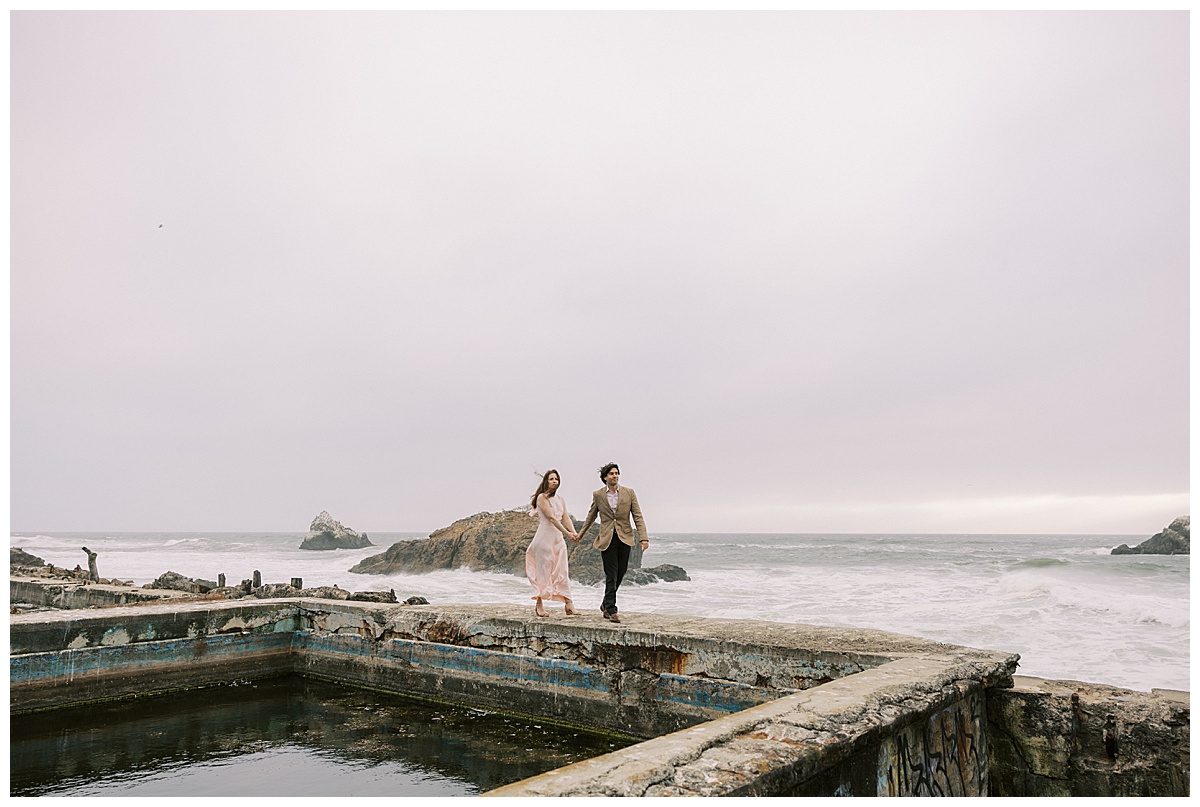 couple walking along ruins up at sutro baths during engagement session