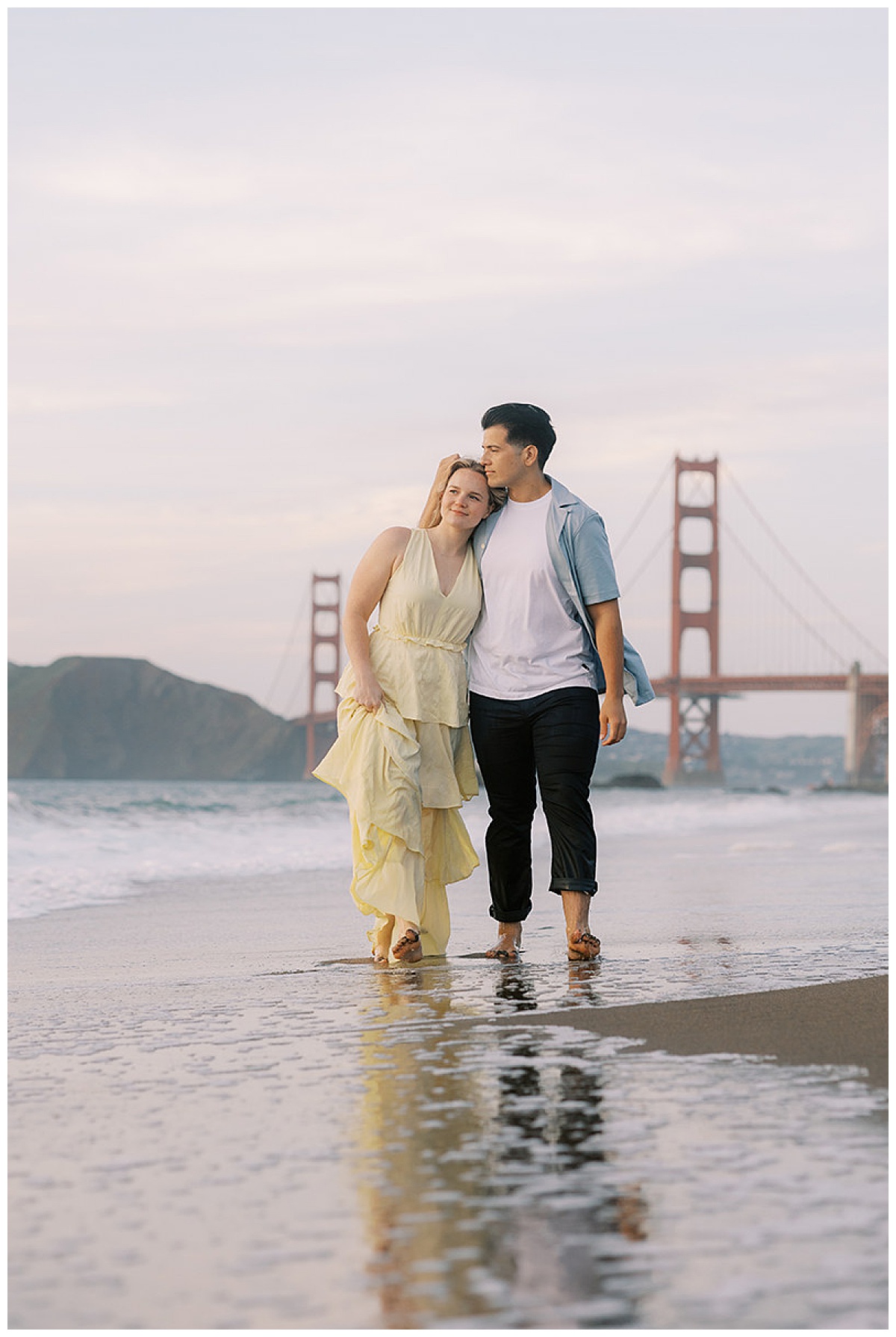 COUPLE WALKING ALONG THE BEACH AT SUNSET AT BAKER BEACH