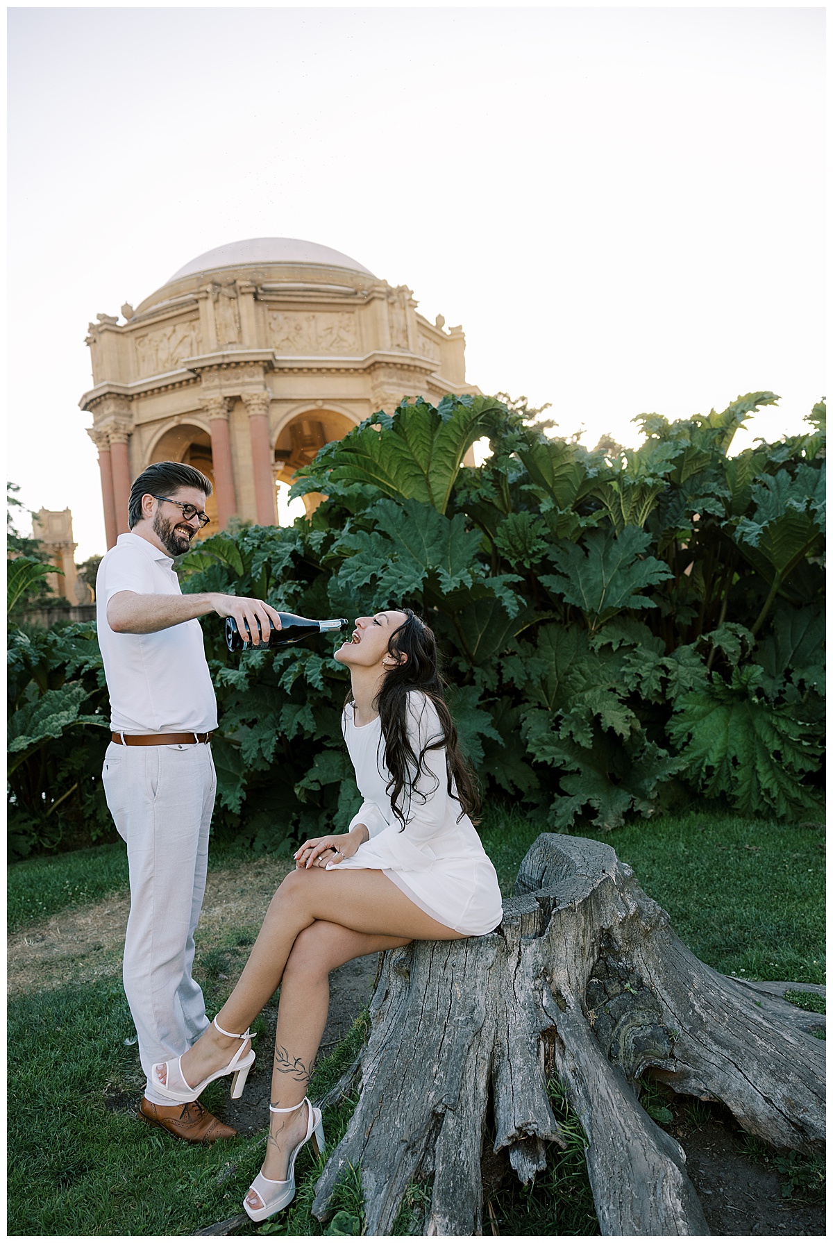 couple drinking champagne in front of palace of fine arts during engagement shoot