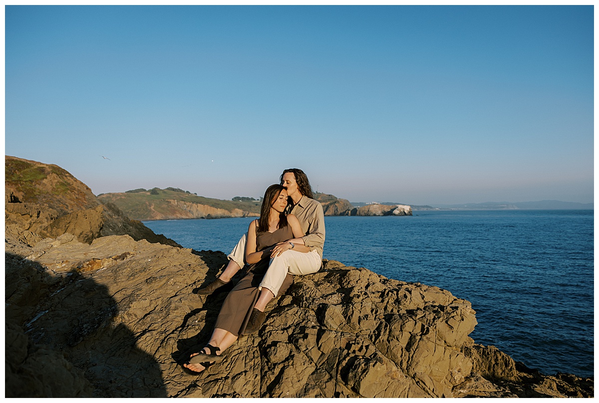 lesbian couple sitting together on cliffside at rodeo beach